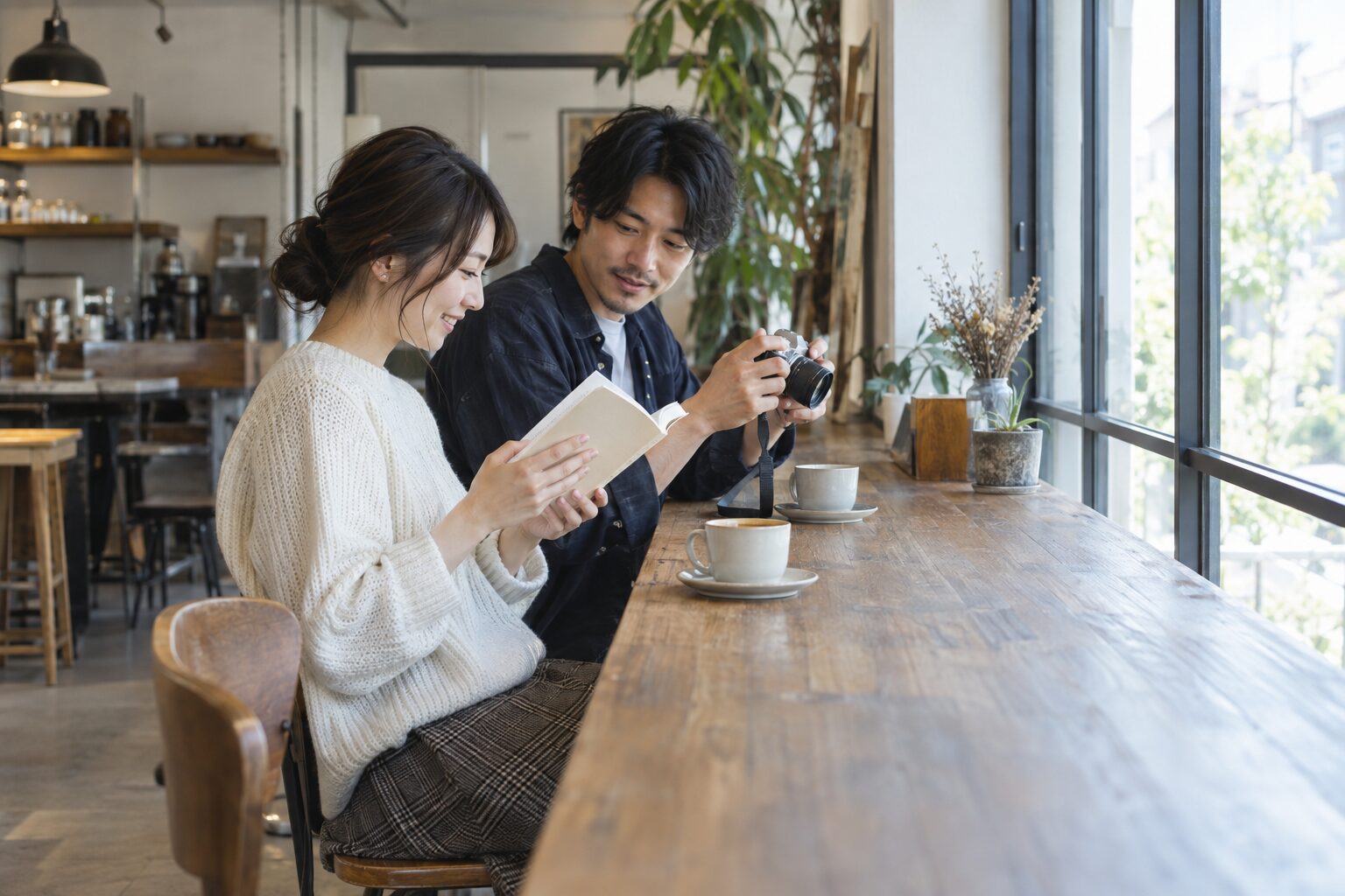 カフェで読書と写真の趣味を楽しみながら会話する二人