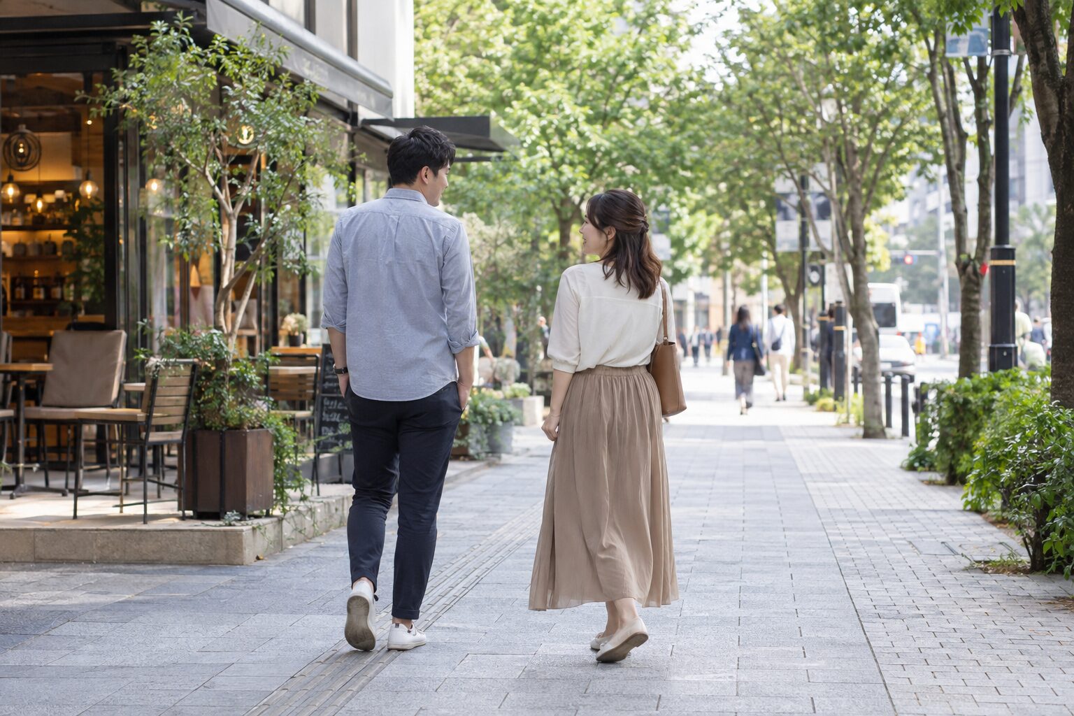 街路樹のある歩道で歩く速さを合わせて会話する二人