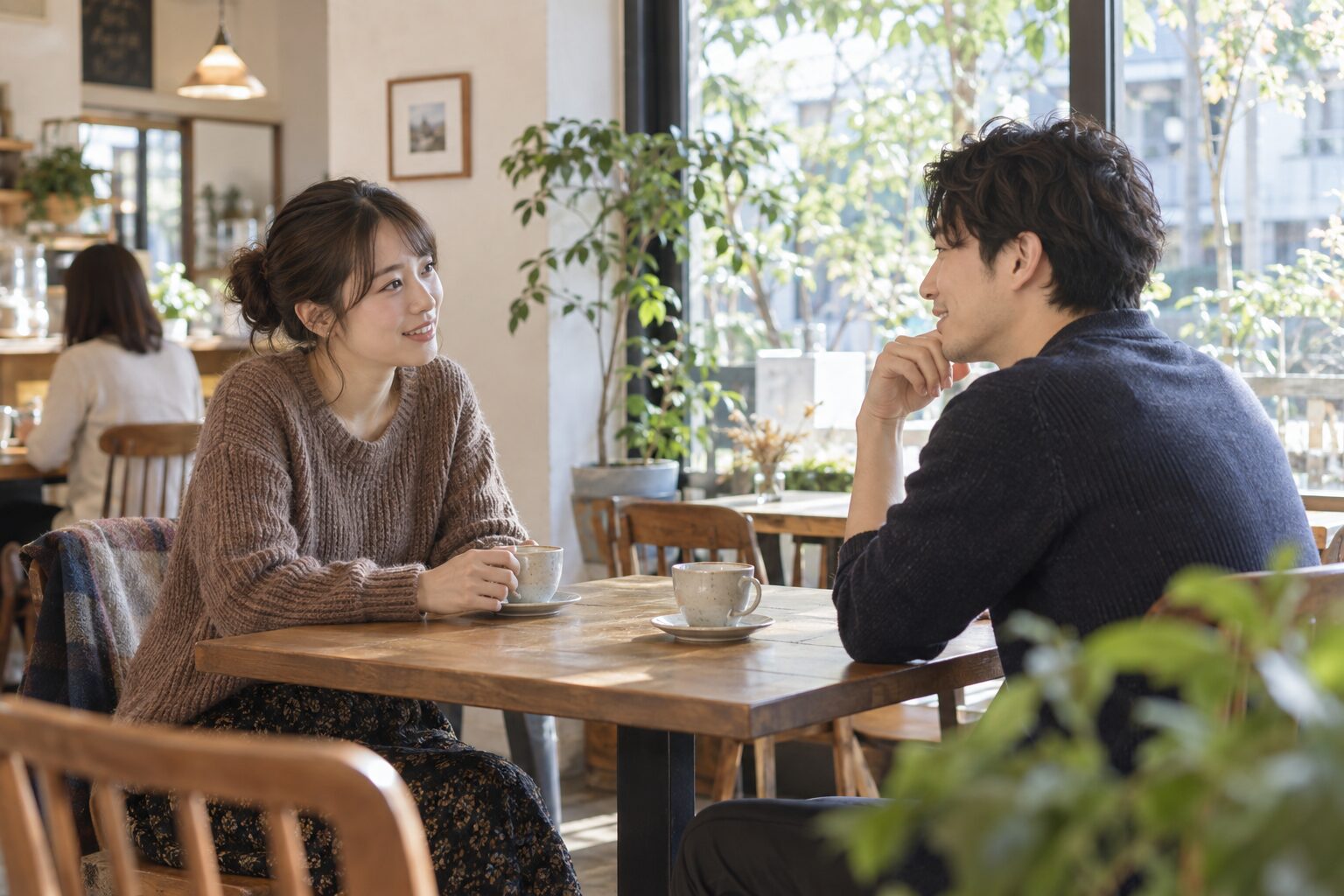 明るいカフェでテーブルを挟み、落ち着いて会話する男女