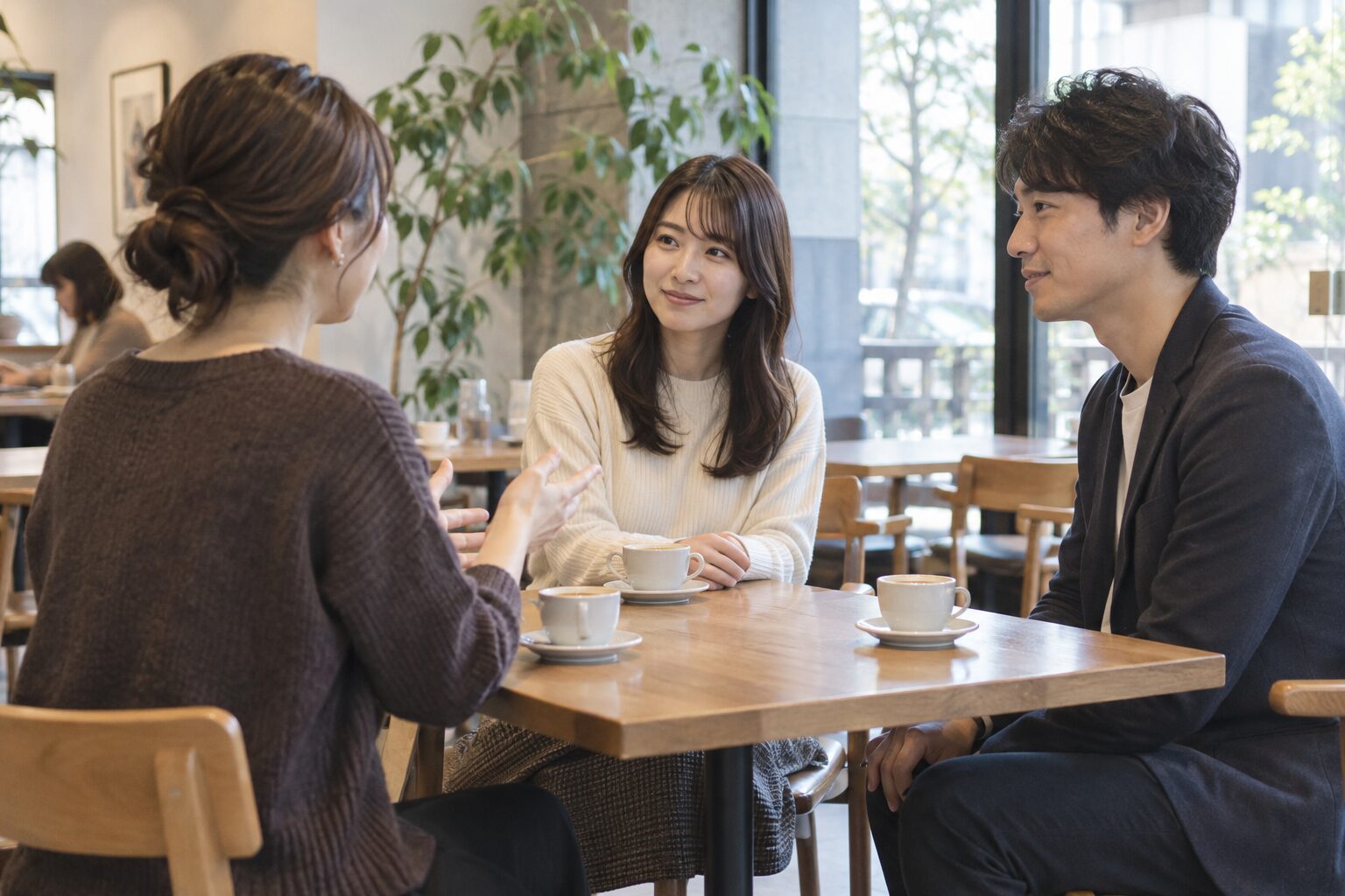 明るいカフェで、共通の友人を交えて初めて会話する三人の男女