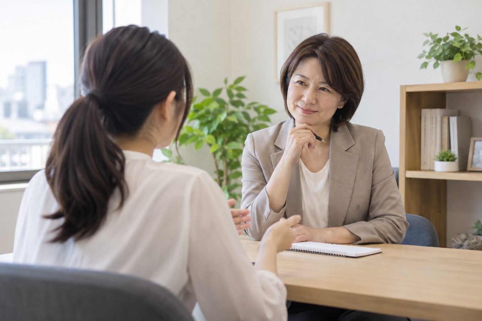 明るい相談室で、ノートを挟んで担当者に希望を伝える相談者